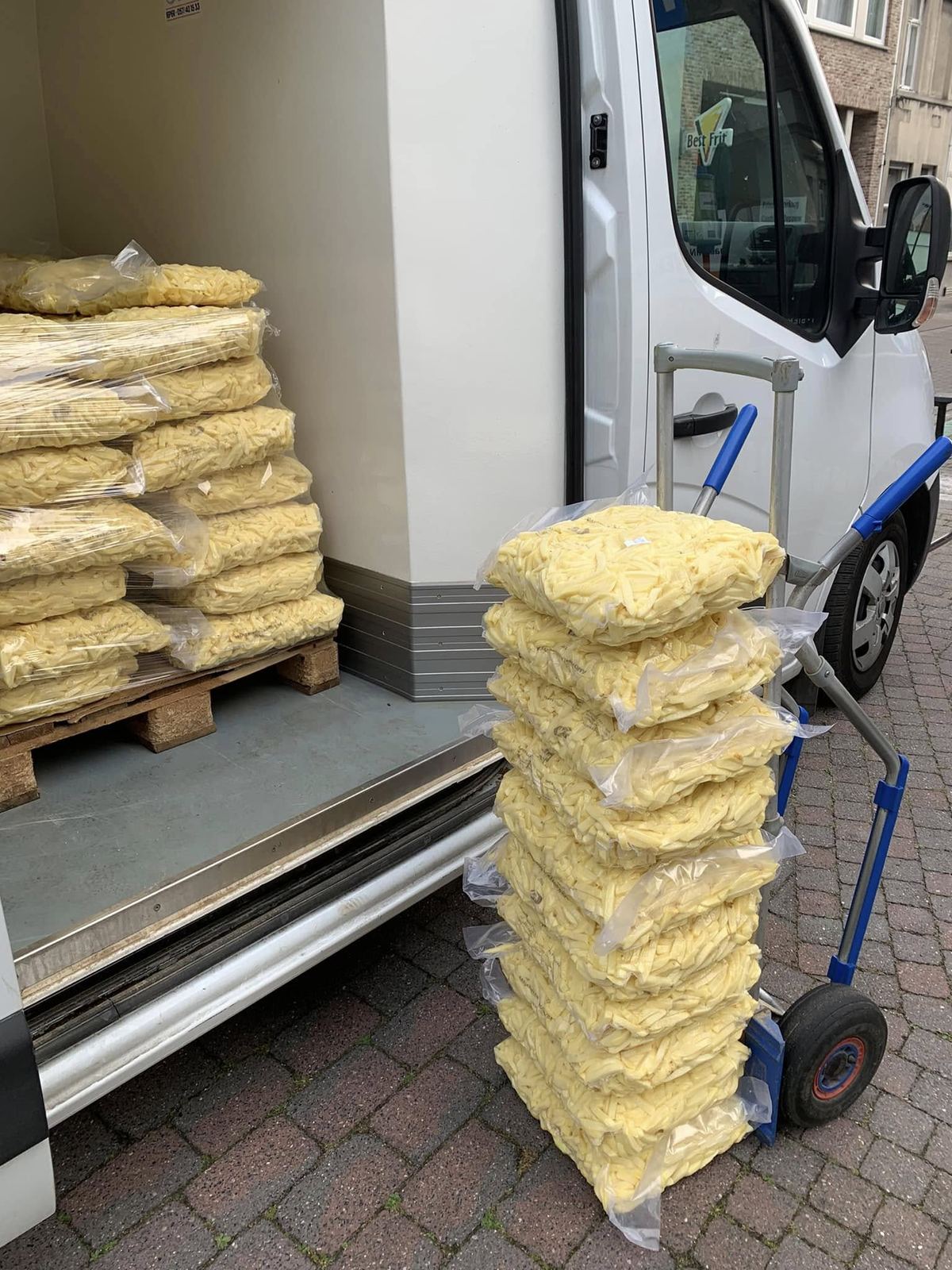 Vacuüm verpakte zakken verse friet, gestapeld op een steekkar naast een koelwagen