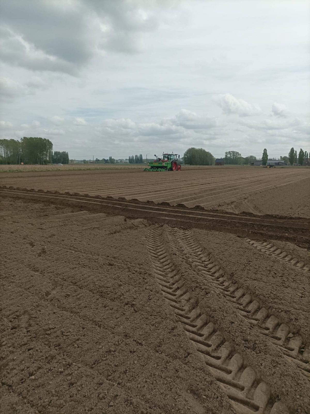 Tractor met pootmachine legt aardappelruggen aan op een pas bewerkt veld